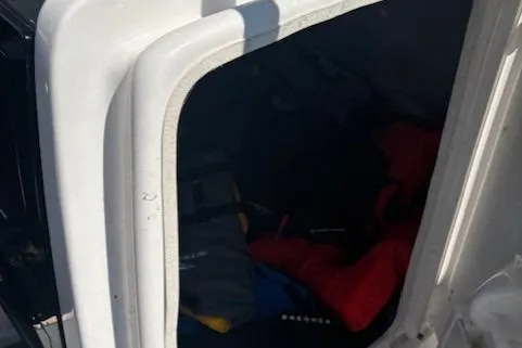 Slide: The Image of Storage compartment on a 2020 Yamaha AR240 boat, partially open with visible gear inside. - 11