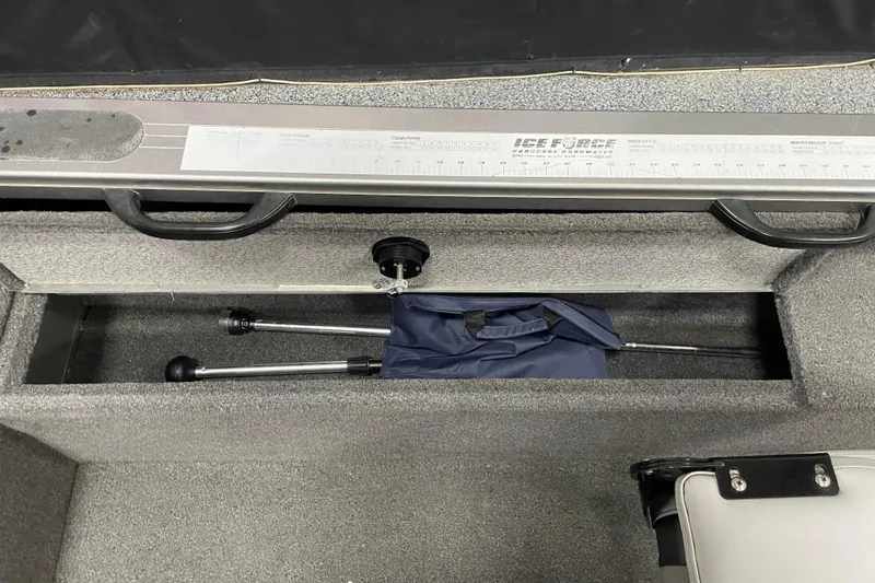 Slide: The Image of 2014 Crestliner 1750 Fish Hawk storage compartment with measuring ruler and folded equipment. - 16