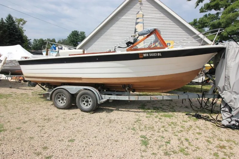 The Image of 1963 Thompson Skiff Craft 21 boat on trailer, parked outdoors near a building. - 1