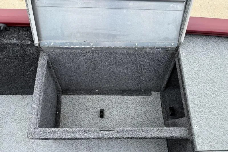 Slide: The Image of Open storage compartment in 2019 Tracker Pro 170 boat, featuring gray carpeted interior. - 14