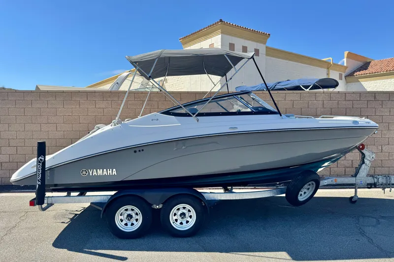 Slide: The Image of 2022 Yamaha Boats 212 on trailer, parked outdoors, with a sunshade canopy. - 0