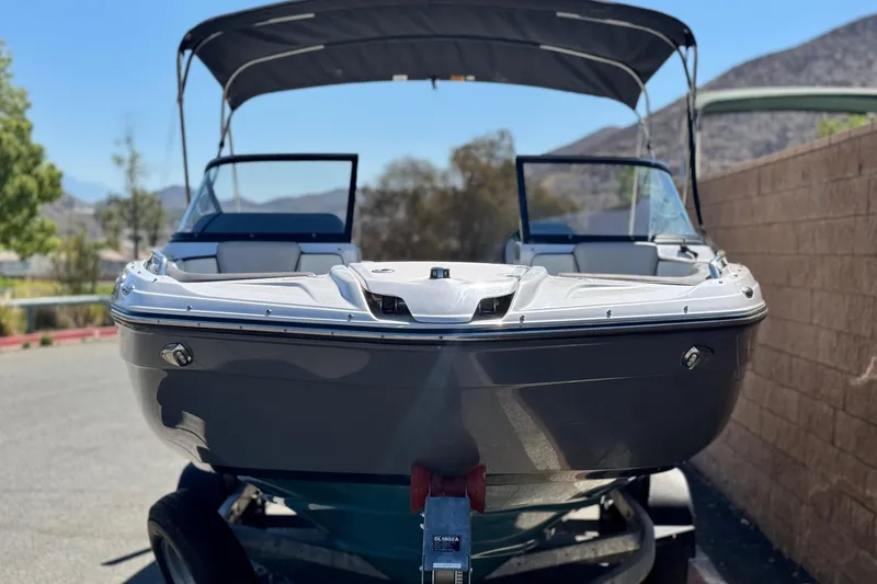 Slide: The Image of 2022 Yamaha Boats 212 with canopy, parked on a trailer, mountain backdrop. - 2
