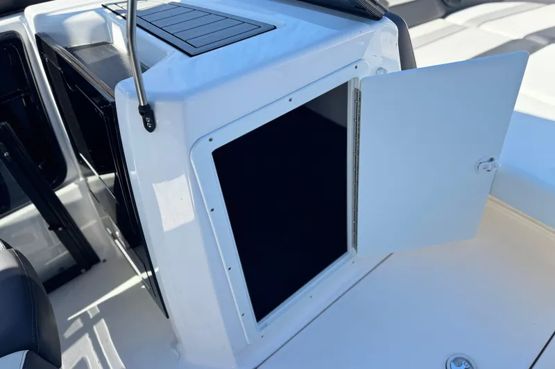 Slide: The Image of 2022 Yamaha Boats 212 interior storage compartment with open door, showcasing sleek design. - 23