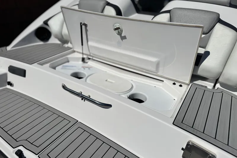Slide: The Image of 2022 Yamaha Boats 212 storage compartment with open hatch and cushioned seating. - 7