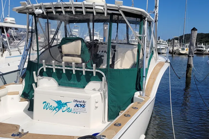The Image of 2002 SeaTek 36 Express boat docked, featuring green canopy and fishing rod holders. - 28