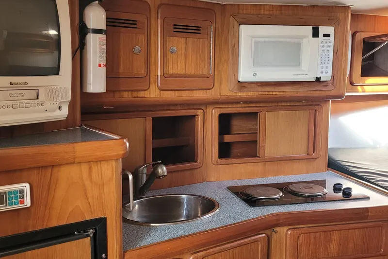 Slide: The Image of 2002 SeaTek 36 Express yacht kitchen with microwave, stove, and wooden cabinetry. - 54