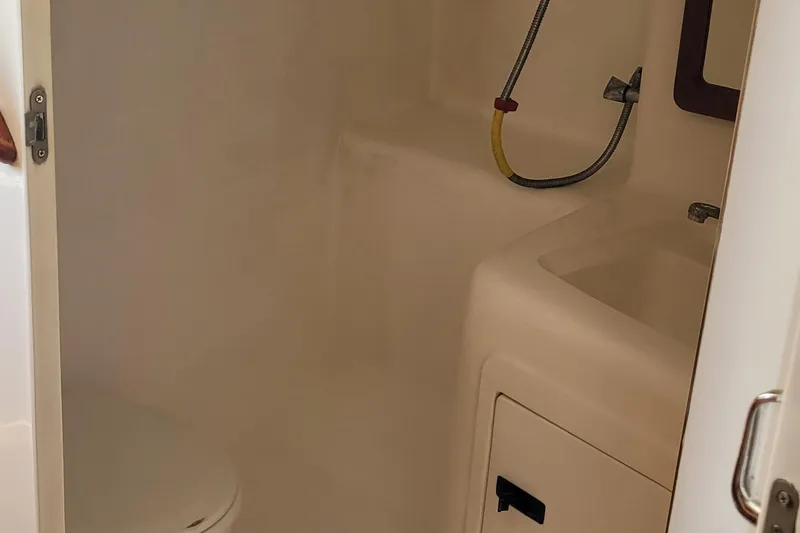 Slide: The Image of 2002 SeaTek 36 Express boat bathroom with toilet, sink, and showerhead. - 57