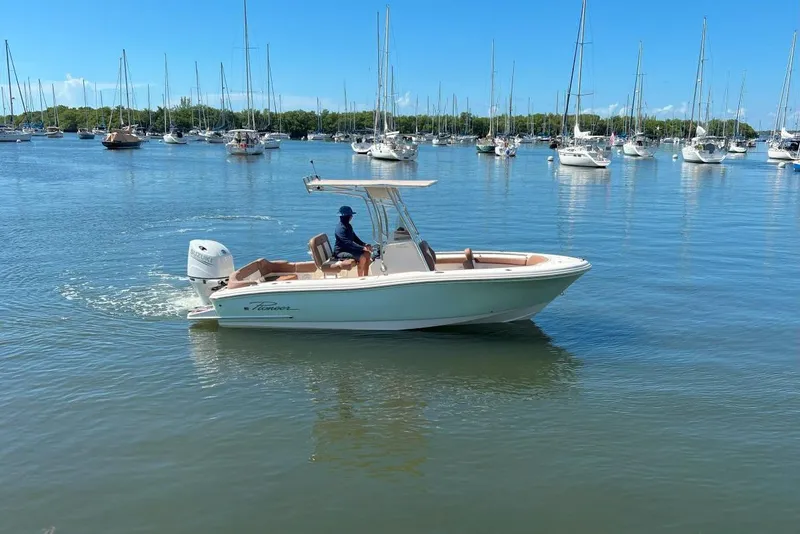 The Image of 2022 Pioneer 202 Islander boat cruising in a marina with sailboats in the background. - 0