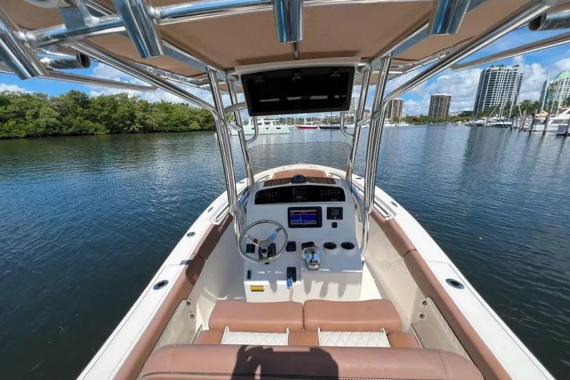 Slide: The Image of 2022 Pioneer 202 Islander boat interior with steering console, on calm water, cityscape background. - 8