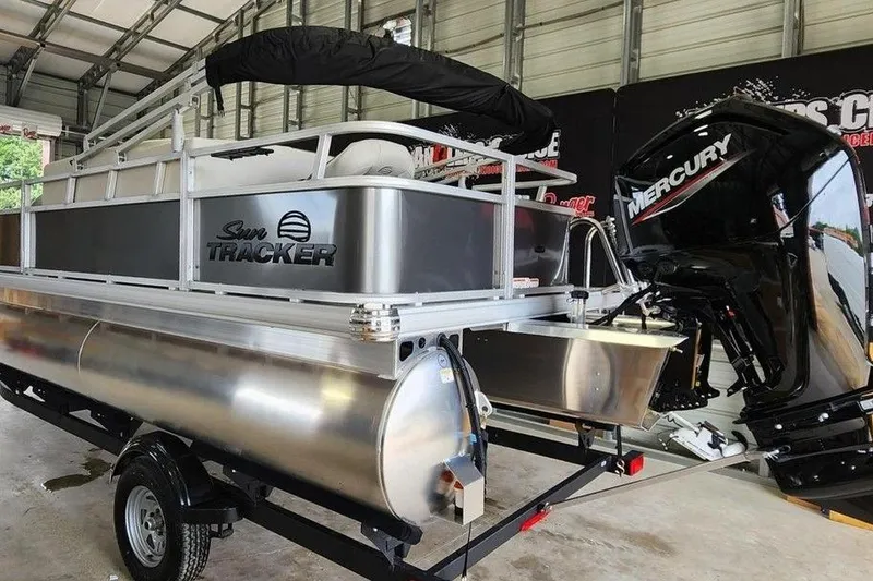 Slide: The Image of 2026 Sun Tracker BASS BUGGY® 18 DLX pontoon boat with Mercury outboard motor in a garage. - 6