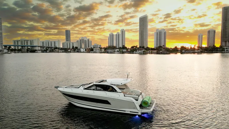 Slide: The Image of 2017 Jeanneau Leader 40 yacht on water at sunset with city skyline backdrop. - 24