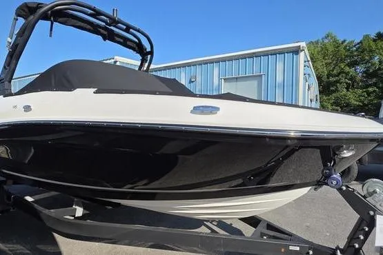 Slide: The Image of 2025 Bayliner VR5 OB boat on trailer, parked near a blue building. - 1