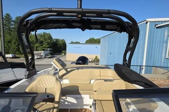 Slide: The Image of 2025 Bayliner VR5 OB boat with tan seating and black canopy, parked outdoors. - 19