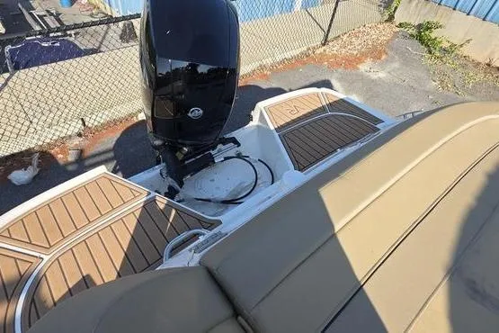 Slide: The Image of 2025 Bayliner VR5 OB boat with tan seating and outboard motor, docked near a fence. - 3