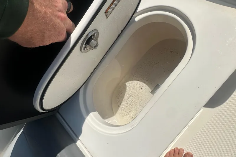 Slide: The Image of 2023 NauticStar 2102 Legacy boat compartment with open hatch, showing interior details. - 20