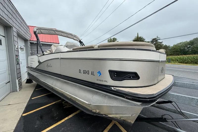 Slide: The Image of 2018 Avalon 2385 Catalina Rear Lounger Tri Toon boat parked near a building. - 11