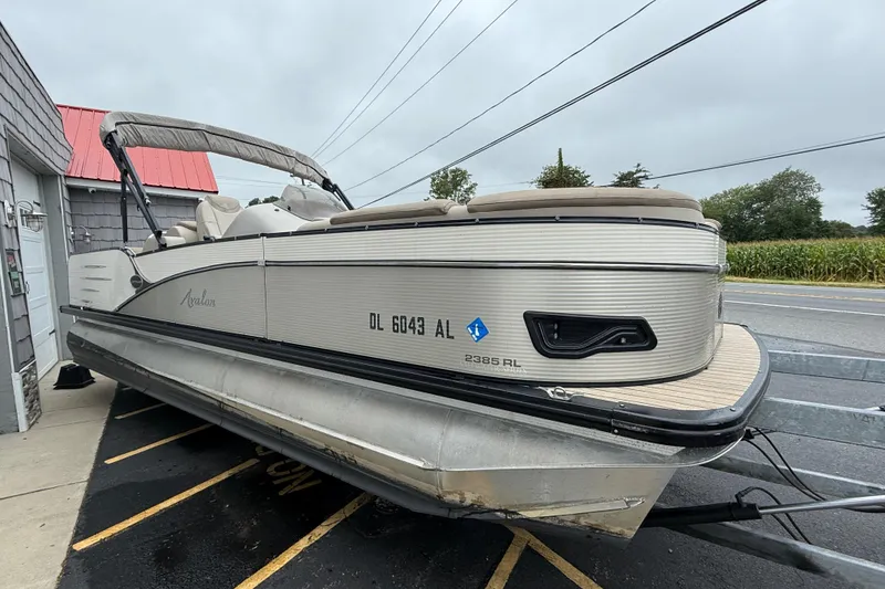 Slide: The Image of 2018 Avalon 2385 Catalina Rear Lounger Tri Toon boat on trailer, parked roadside. - 12