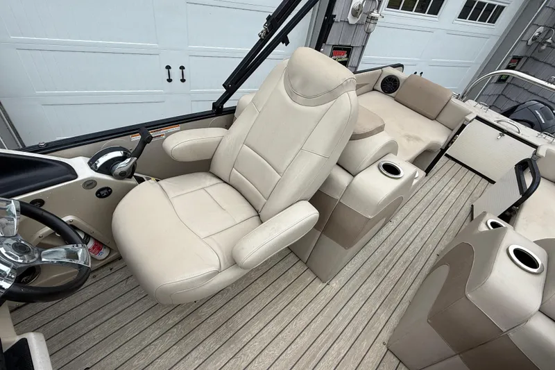 Slide: The Image of 2018 Avalon 2385 Catalina Rear Lounger boat interior with beige seating and steering wheel. - 20