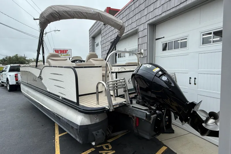 Slide: The Image of 2018 Avalon 2385 Catalina Rear Lounger Tri-Toon boat with high-performance engine, parked outdoors. - 7