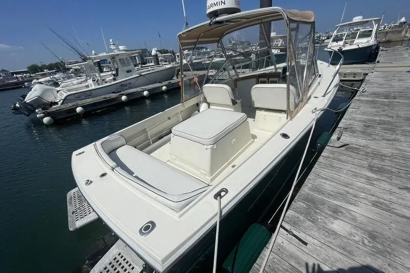 Slide: The Image of 2004 Limestone 24 boat docked at marina, featuring spacious seating and canopy. - 6