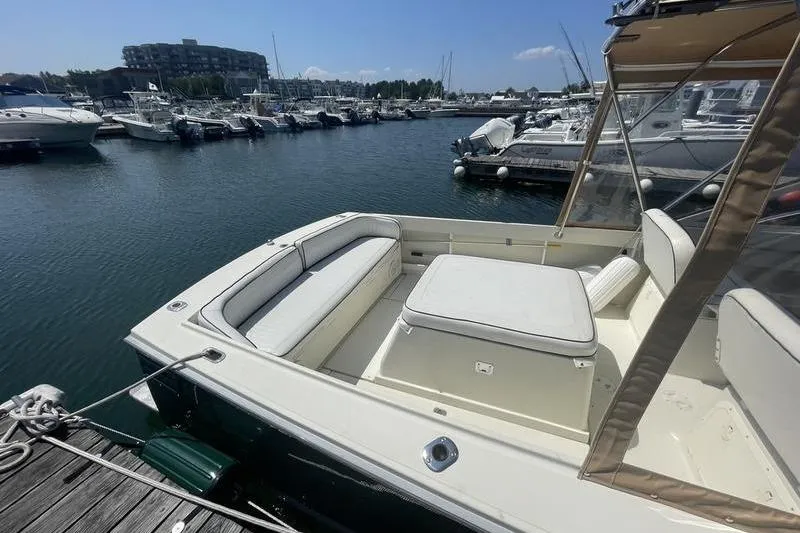 Slide: The Image of 2004 Limestone 24 boat docked at marina, featuring spacious seating and clear skies. - 7