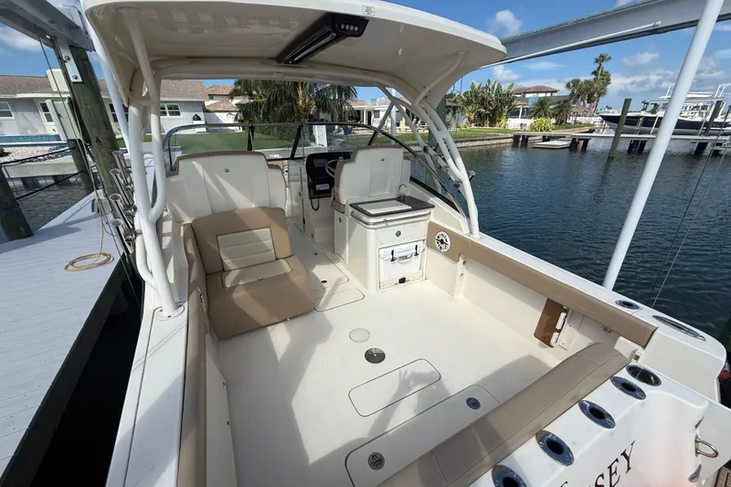 Slide: The Image of 2023 Scout 255 Dorado boat interior with seating and helm, docked by the water. - 11