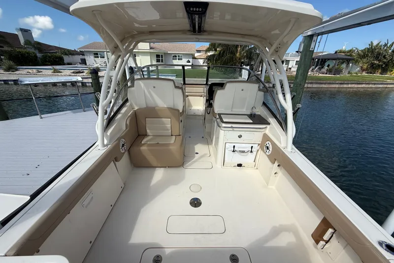 Slide: The Image of 2023 Scout 255 Dorado boat interior with seating and storage, docked by waterfront homes. - 12