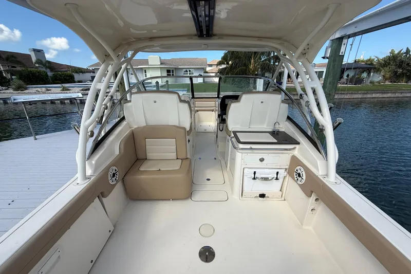 Slide: The Image of 2023 Scout 255 Dorado boat interior with seating and helm, docked by waterfront homes. - 13