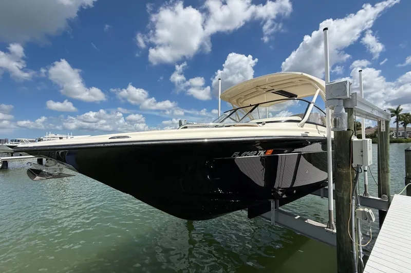 Slide: The Image of 2023 Scout 255 Dorado boat on lift, under a clear blue sky with clouds. - 4