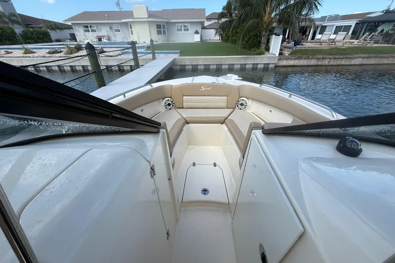 Slide: The Image of 2023 Scout 255 Dorado boat interior with beige seating, docked by waterfront homes. - 43