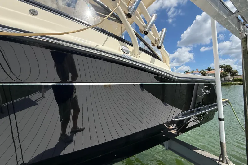 Slide: The Image of 2023 Scout 255 Dorado boat docked, reflecting clear blue sky and water. - 6