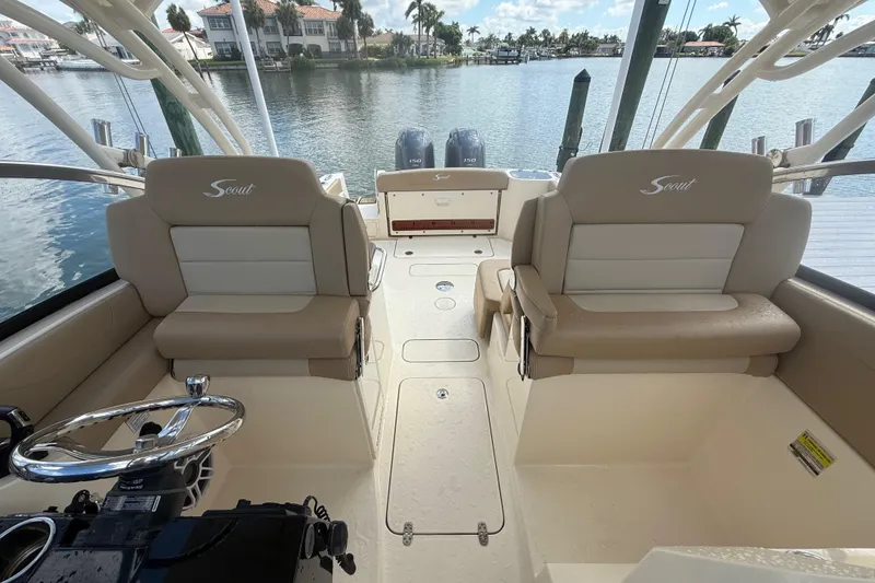 Slide: The Image of 2023 Scout 255 Dorado boat interior with dual seating and steering wheel, docked by the water. - 66