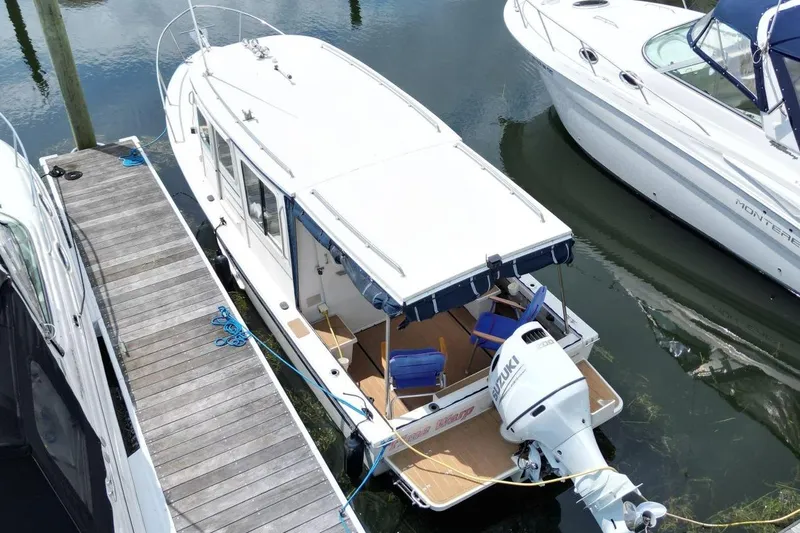 Slide: The Image of 2002 Rosborough RF-246 Sedan Cruiser docked, featuring a Suzuki outboard motor and spacious deck. - 6