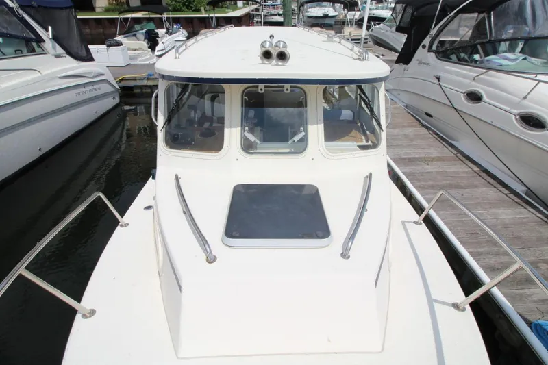 Slide: The Image of 2002 Rosborough RF-246 Sedan Cruiser docked between boats, showcasing its cabin and deck. - 8