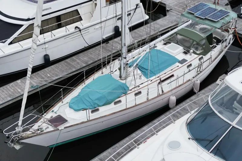 The Image of Sailboat docked at marina, Passport 47 model, 1985, with solar panels and teal covers. - 0