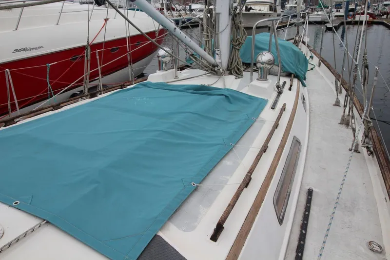 Slide: The Image of 1985 Passport 47 sailboat deck with teal cover, docked in marina. - 11