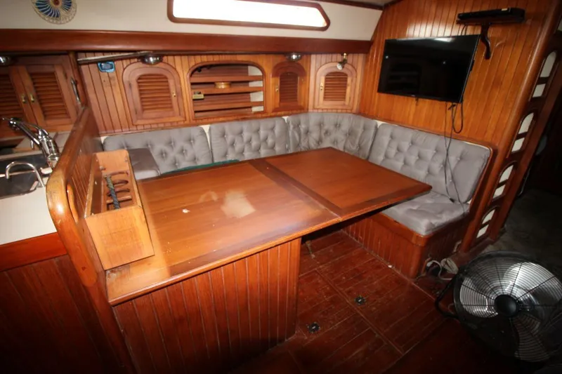 Slide: The Image of Cozy 1985 Passport 47 yacht interior with wooden dining area and cushioned seating. - 18