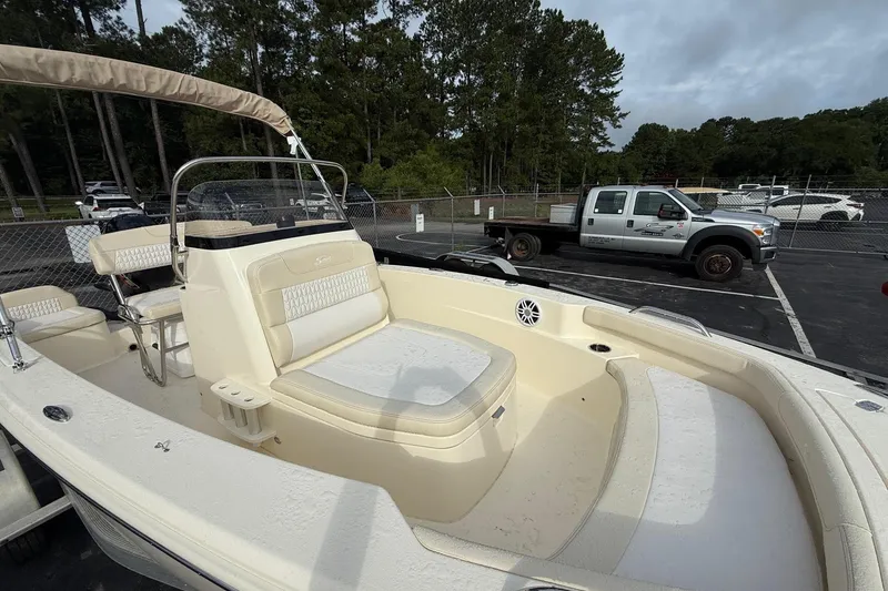Slide: The Image of 2026 Scout 188 Sportfish boat with seating, parked in a lot with trees and vehicles. - 14