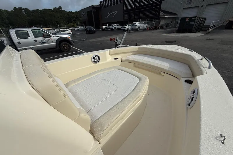 Slide: The Image of 2026 Scout 188 Sportfish boat interior with beige seating and speakers, parked outdoors. - 15