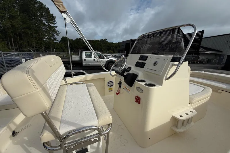 Slide: The Image of 2026 Scout 188 Sportfish boat interior with steering console and seating, parked outdoors. - 16