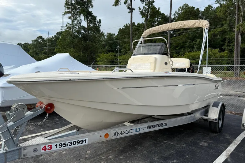 Slide: The Image of 2026 Scout 188 Sportfish boat on trailer, parked outdoors with trees in background. - 4