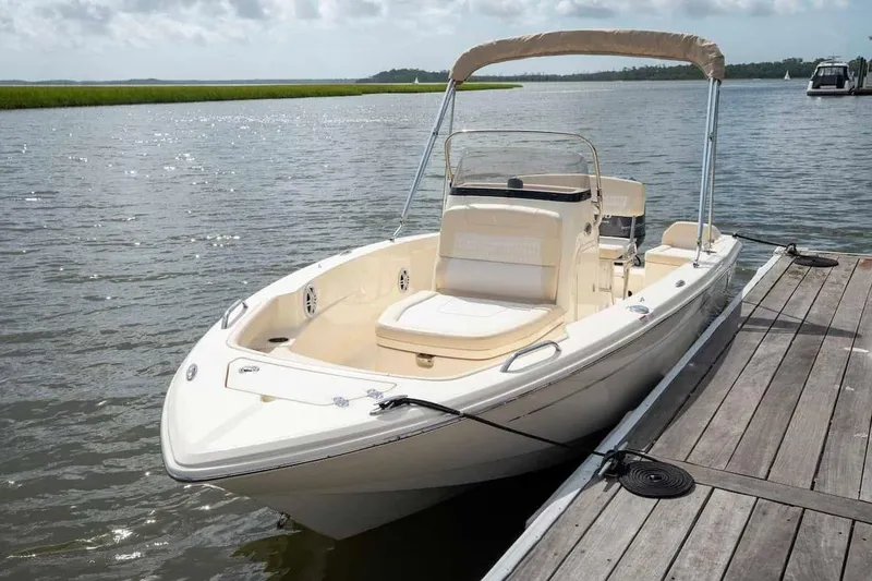 Slide: The Image of 2026 Scout 188 Sportfish boat docked on a sunny day by the water. - 5