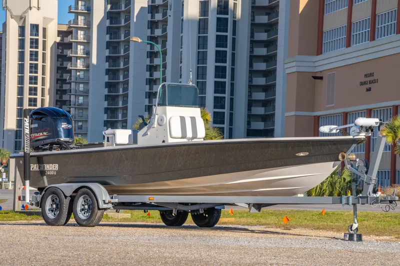 Slide: The Image of 2001 Pathfinder 2400-V boat on trailer, parked near modern buildings. - 2