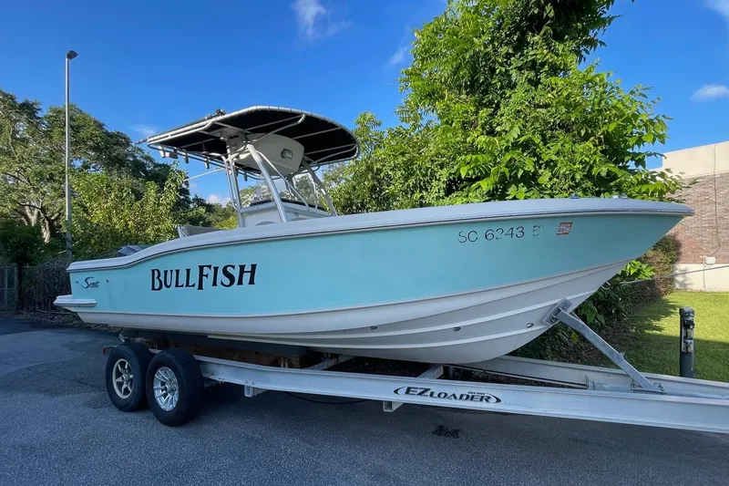 Slide: The Image of 2006 Scout 242 Sportfish boat on trailer, labeled "BullFish," parked outdoors. - 4