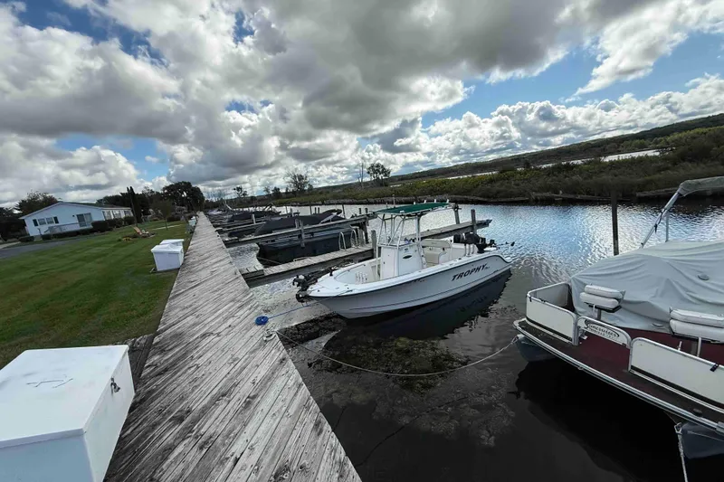 Slide: The Image of Docked boats by a wooden pier under a cloudy sky, featuring a 2007 Formula 27 Performance Cruiser. - 4
