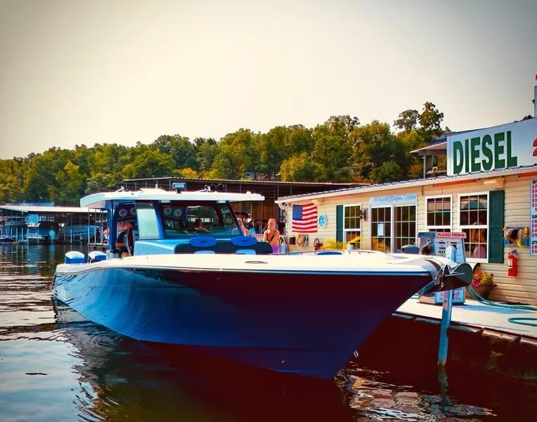 Slide: The Image of 2025 HCB 48 Campeon boat docked near a lakeside fuel station. - 19