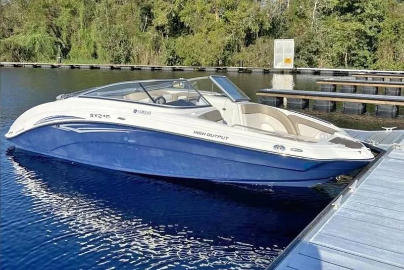 The Image of 2011 Yamaha Boats SX240 HO docked on calm water, surrounded by lush greenery. - 0