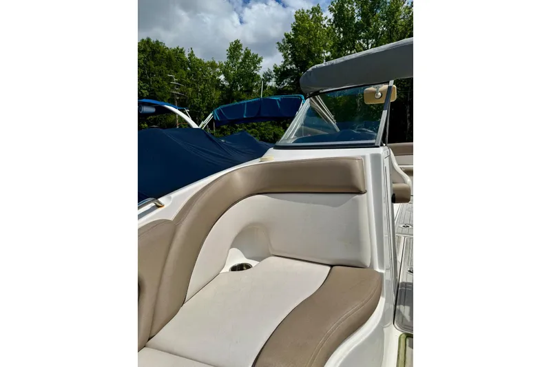 Slide: The Image of 2011 Yamaha Boats SX240 HO interior with beige seating and canopy, surrounded by trees. - 12