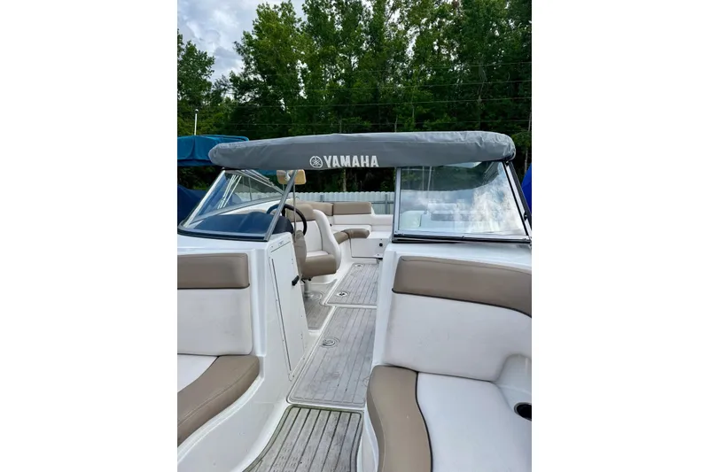 Slide: The Image of 2011 Yamaha Boats SX240 HO interior with beige seating and canopy, surrounded by trees. - 6