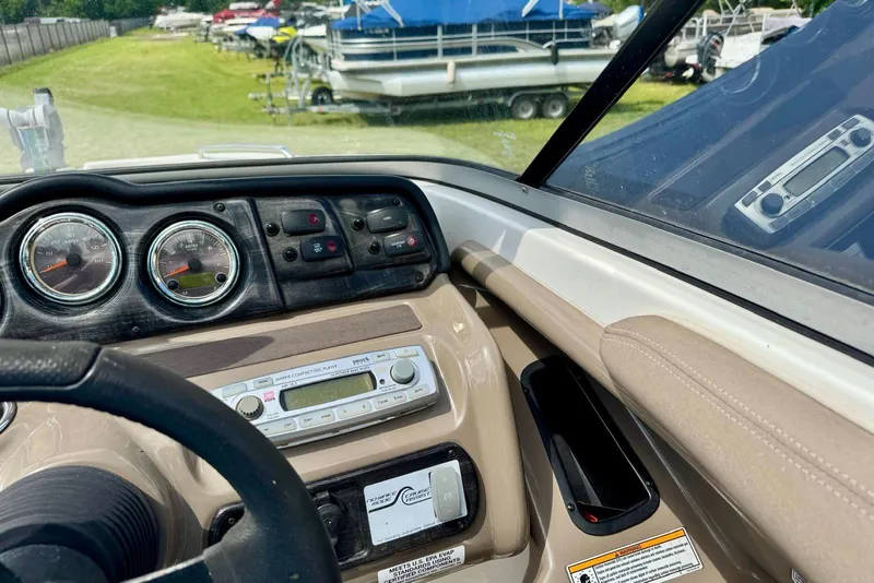 Slide: The Image of 2011 Yamaha Boats SX240 HO dashboard with gauges and controls, parked near other boats. - 9